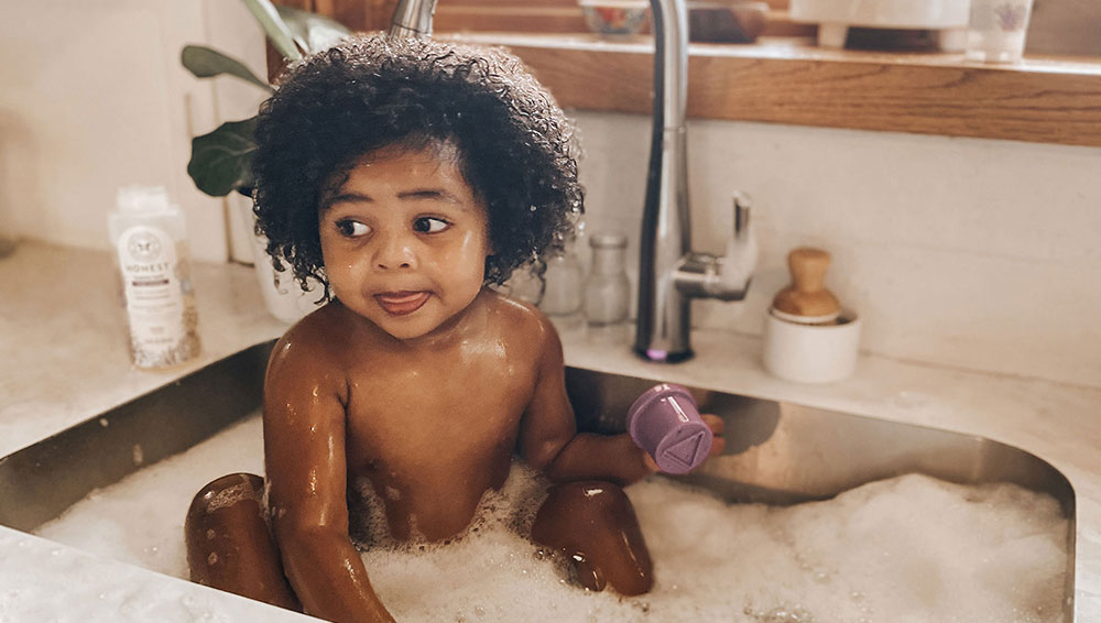 Baby taking a bath in kitchen sink for The Honest Company influencer campaign